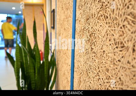 A close-up view of textured acoustic wall panels made of compressed wood wool fibers in a modern office interior. The panels feature a natural beige Stock Photo