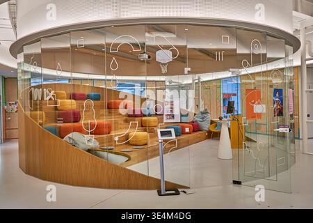 Interior view of a modern, circular conference room enclosed by curved floor-to-ceiling glass walls decorated with white abstract line graphics Stock Photo