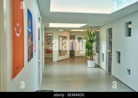 A bright, modern hallway interior featuring clean white walls and polished concrete flooring. The corridor is illuminated by large rectangular Stock Photo