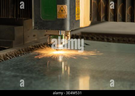 High-Precision Laser Cutting Machine Creating Sparks While Processing Metal Sheet on Industrial Workstation Stock Photo