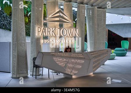 Modern reception area of Parktown Business Center featuring an angular geometric reception desk with perforated backlit metal panels displaying Stock Photo