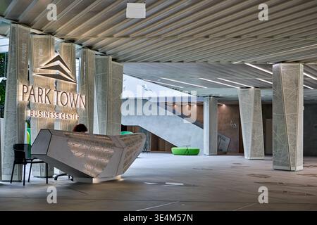 Modern interior lobby of Park Town Business Center featuring an angular geometric reception desk with metallic textured surfaces. The space includes Stock Photo