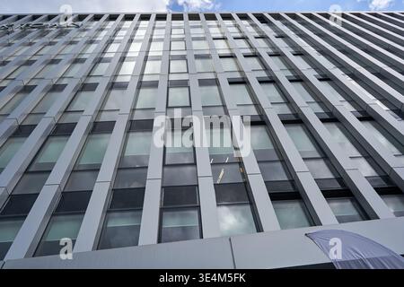 Modern corporate office building facade featuring a geometric grid pattern of vertical white structural beams alternating with horizontal bands of Stock Photo