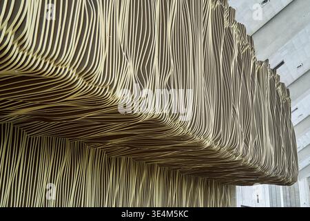 Close-up architectural photograph showcasing a contemporary building facade featuring undulating, layered panels with a distinctive striped pattern. Stock Photo