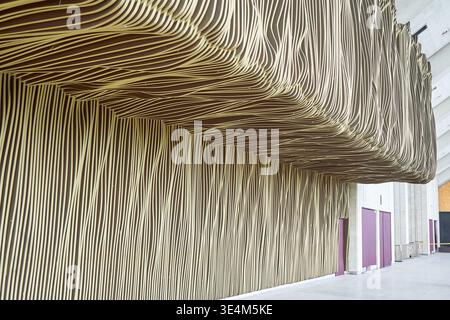 A large-scale architectural installation featuring undulating striped fabric covering interior walls and ceiling in a modern building. The artwork Stock Photo
