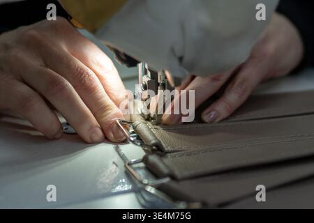 Intricate Craftsmanship: A Close-Up of a Skilled Seamstress at Work with Sewing Machine on Leather Material Stock Photo