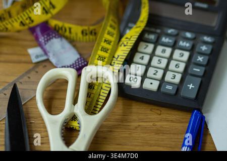 A Collection of Crafting Tools Including Scissors, Measuring Tape, and a Calculator on a Wooden Workspace Stock Photo
