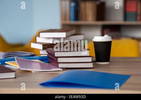 A Cozy Study Scene Featuring Stacked Books and Paperwork with a Coffee Cup on a Modern Workspace Table Stock Photo