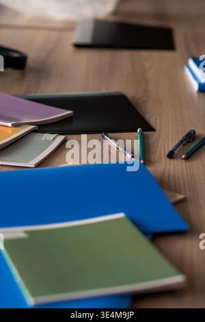 An Organized Collection of Colorful Notebooks and Stationery Items on a Wooden Table Surface Stock Photo