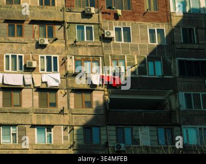 Urban Apartment Building With Laundry Hanging on Balconies and Air Conditioners in Afternoon Light, houseblock in Yerevan Stock Photo