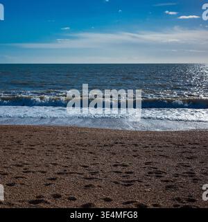 Seascape in Early Spring with sunshine reflecting off incoming waves on a shingle beach. Stock Photo