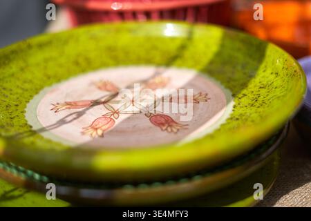 Close-up of handmade ceramic plates stacked together, featuring a vibrant green glazed surface with black speckles. The top plate displays a Stock Photo