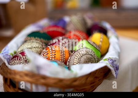 A wicker basket filled with colorful hand-decorated Easter eggs featuring intricate traditional patterns including dots, lines, and geometric designs Stock Photo
