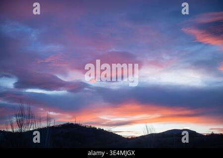 Colorful sunset with dramatic pink and blue clouds over a mountain horizon. Peaceful landscape with soft light and natural atmosphere, ideal for backg Stock Photo