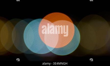 Abstract night background with colorful blurry bokeh lights in orange, blue, and white tones. Soft out of focus circular shapes on dark background. Stock Photo