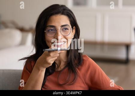 Woman holding smartphone, speaking on speakerphone or using voice assistant Stock Photo