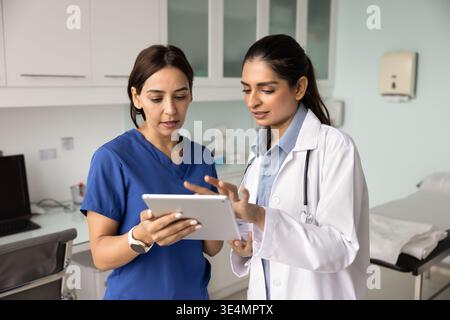 Two multiethnic women doctors reviewing test results using digital tablet Stock Photo