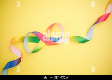 Rainbow Infinity Satin Ribbon on Yellow Background Representing Autism Acceptance and Neurodiversity Concept Stock Photo