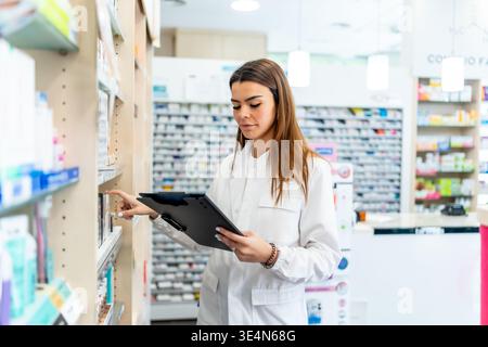 Female pharmacist checking medical stock on pharmacy shelves Stock Photo