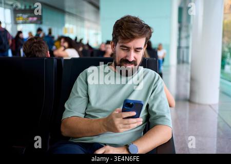 Smiling man using smartphone at airport gate Stock Photo