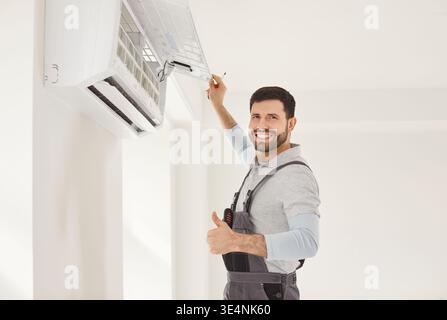Service man working on wall mounted air conditioner unit, professional man smiling thumbs up gesture Stock Photo