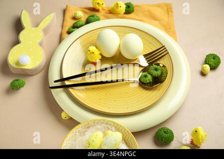 Stylish table setting for Easter celebration with flowers on beige background Stock Photo