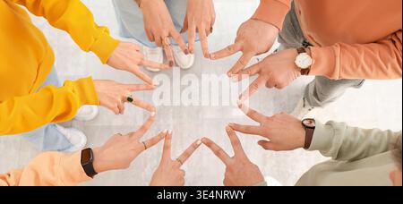 Group of people putting fingers together indoors, top view Stock Photo