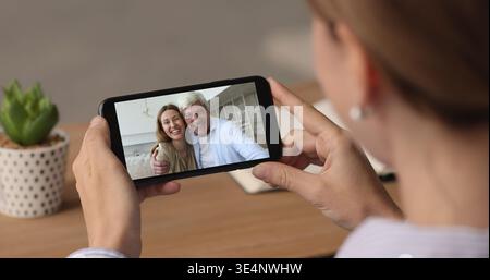 Female hold smartphone engaged in virtual meeting with family Stock Photo
