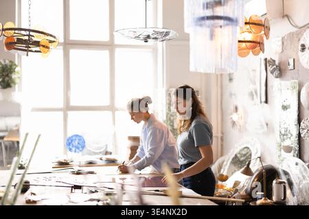 Two female artisans working on glasswork project in workshop studio Stock Photo