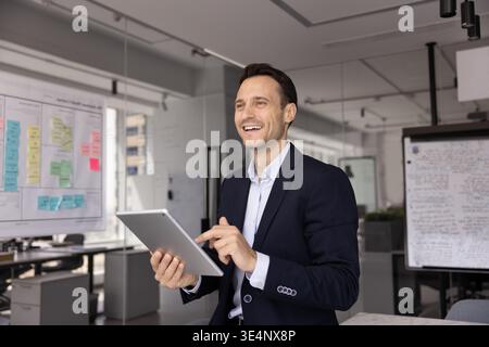 Motivated businessman looking forward with smile distracted from using pad Stock Photo