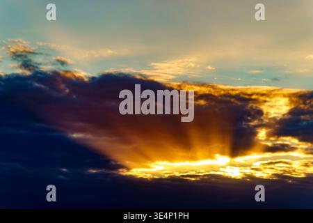 Bright suns rays glow through dark clouds at sunrise in Tauranga sky. Stock Photo