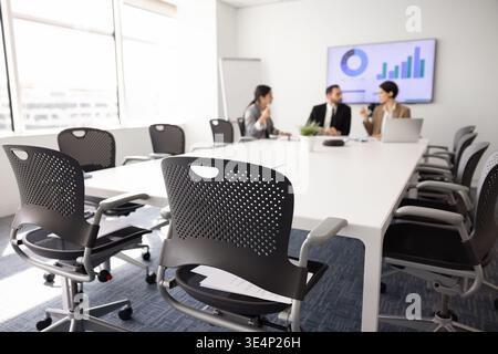 Businesspeople sit around conference table, discussing strategy, analyzing data Stock Photo