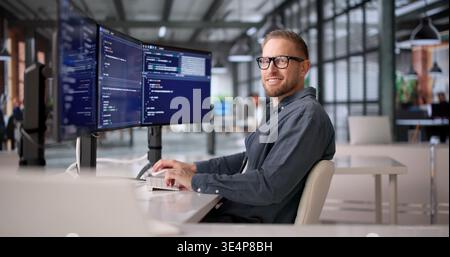 Joyful Software Developer Coding With Several Screens In Office Setting Stock Photo
