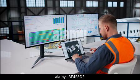 Aerospace Engineer Conducts Aircraft Engine Inspection With Laptop In Hangar Stock Photo