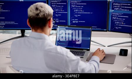 Hispanic Male Software Developer Working On Coding And Tech Solutions At Office Desk Stock Photo