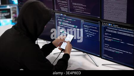 Experienced Hacker Methodically Attempts To Unlock Smartphone PIN In Dark Setting Stock Photo