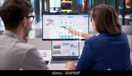 Business Analyst Reviewing Financial Dashboard On Desktop In Modern Office Environment Stock Photo