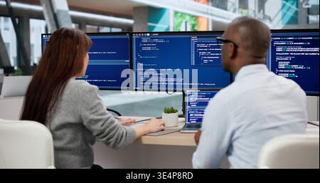 Two Young Software Developers Coding Together At Their Office Desk. Focused Engineers Analyzing Data Stock Photo