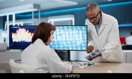 Two Scientists, A Man And Woman, Study Data On Computer Screens In A Lab; They Could Be Researchers Stock Photo
