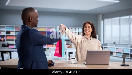 Young Man Making Contactless Payment At Tailor Shop, Consulting Designer; Could Be Customer, Store Owner Stock Photo