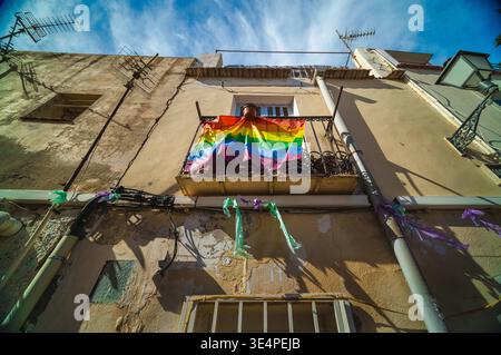 Rainbow flag hanging from a small balcony on an old Mediterranean building under bright blue sky in Alicante, Spain. Stock Photo