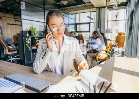 Caucasian specialist studying financial charts while on call Stock Photo