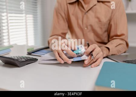 Close up of person organizing financial documents with clips on desk, representing paperwork management, accounting process, office organization, and Stock Photo