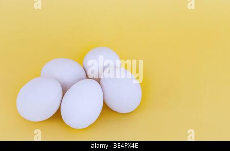 Whole white eggs. Fresh organic white chicken eggs on the yellow background, close up, copy space for text, nobody. Healthy eating concept Stock Photo
