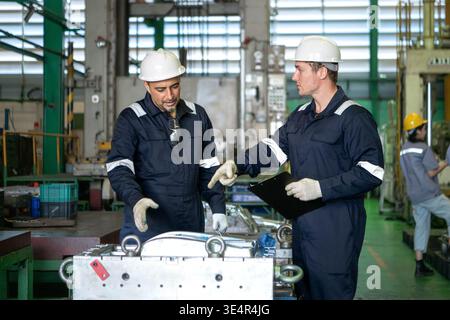 Industrial engineers and technicians discussing machine operation while inspecting equipment in a manufacturing factory || Model released Stock Photo