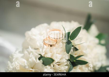 Wedding rings on the wedding bouquet of white roses. Stock Photo