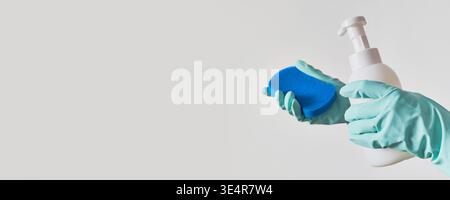 Hands in protective gloves holding cleaning sponge and soap dispenser, banner format Stock Photo