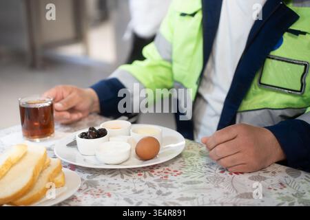 Industrial engineers sitting in canteen and talking on lunch break. Construction company workers in safety uniform eating meal and chatting in modern Stock Photo