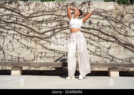 Dancer prepares for performance. Contemporary woman performer stands before textured vine wall Stock Photo