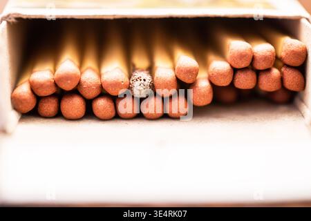 Close-up of a matchbox filled with wooden matches, with one burned match head among unburned match tips inside the box. Stock Photo